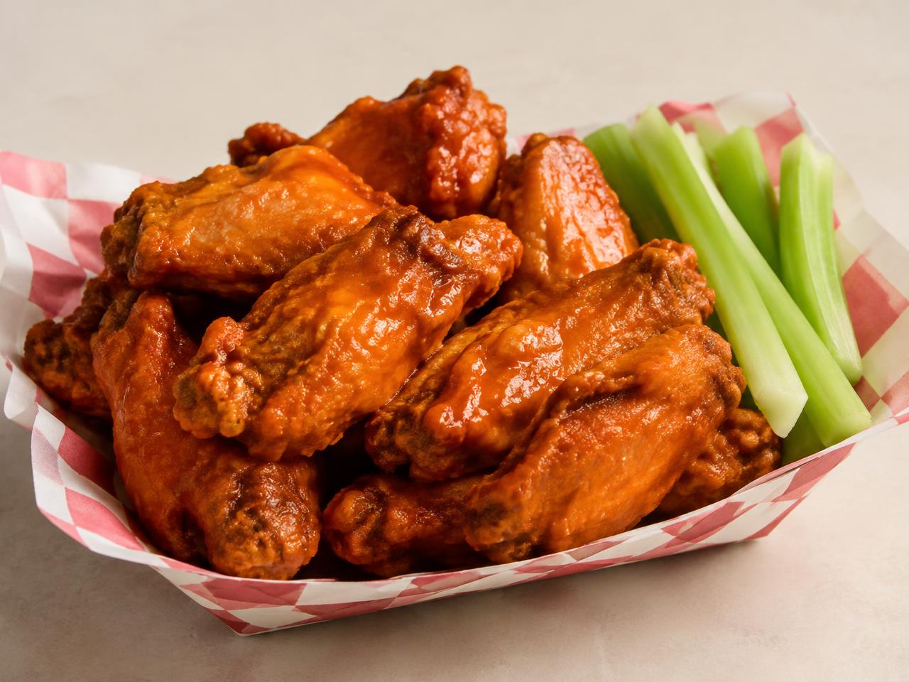 Crispy buffalo chicken wings in a paper tray with celery